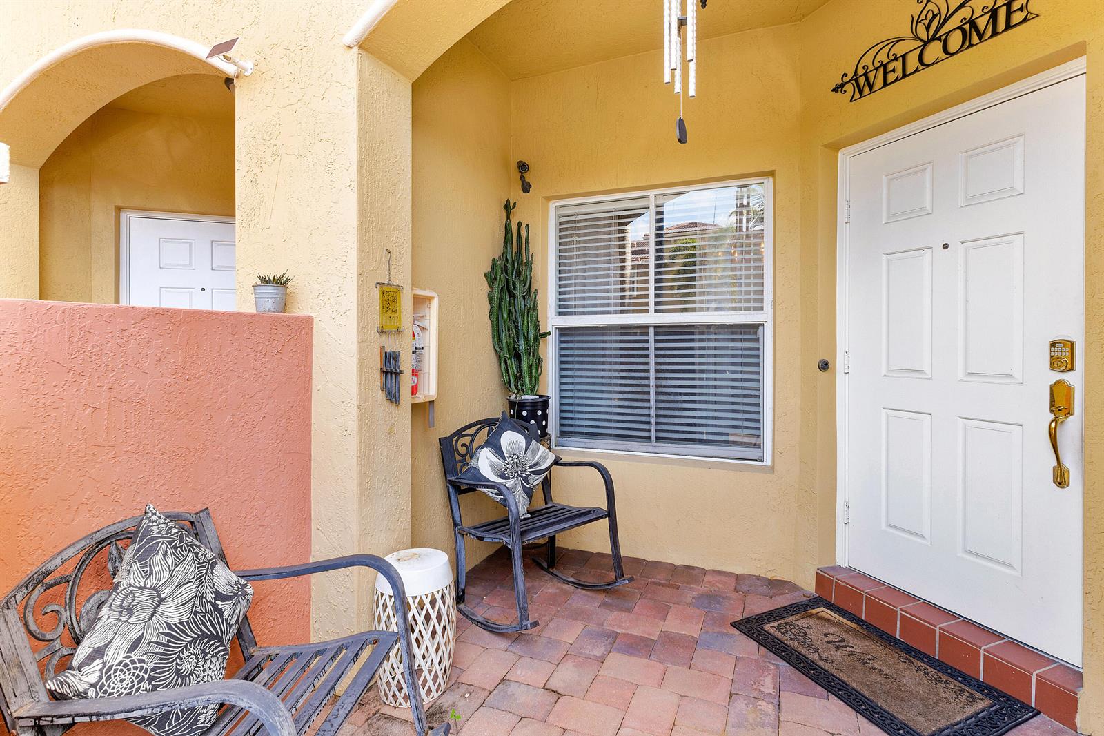A covered patio features a brick floor, two metal chairs, a cactus, and a white door — 2851 W Prospect # 506, Tamarac FL 33309, TAMARAC, FL