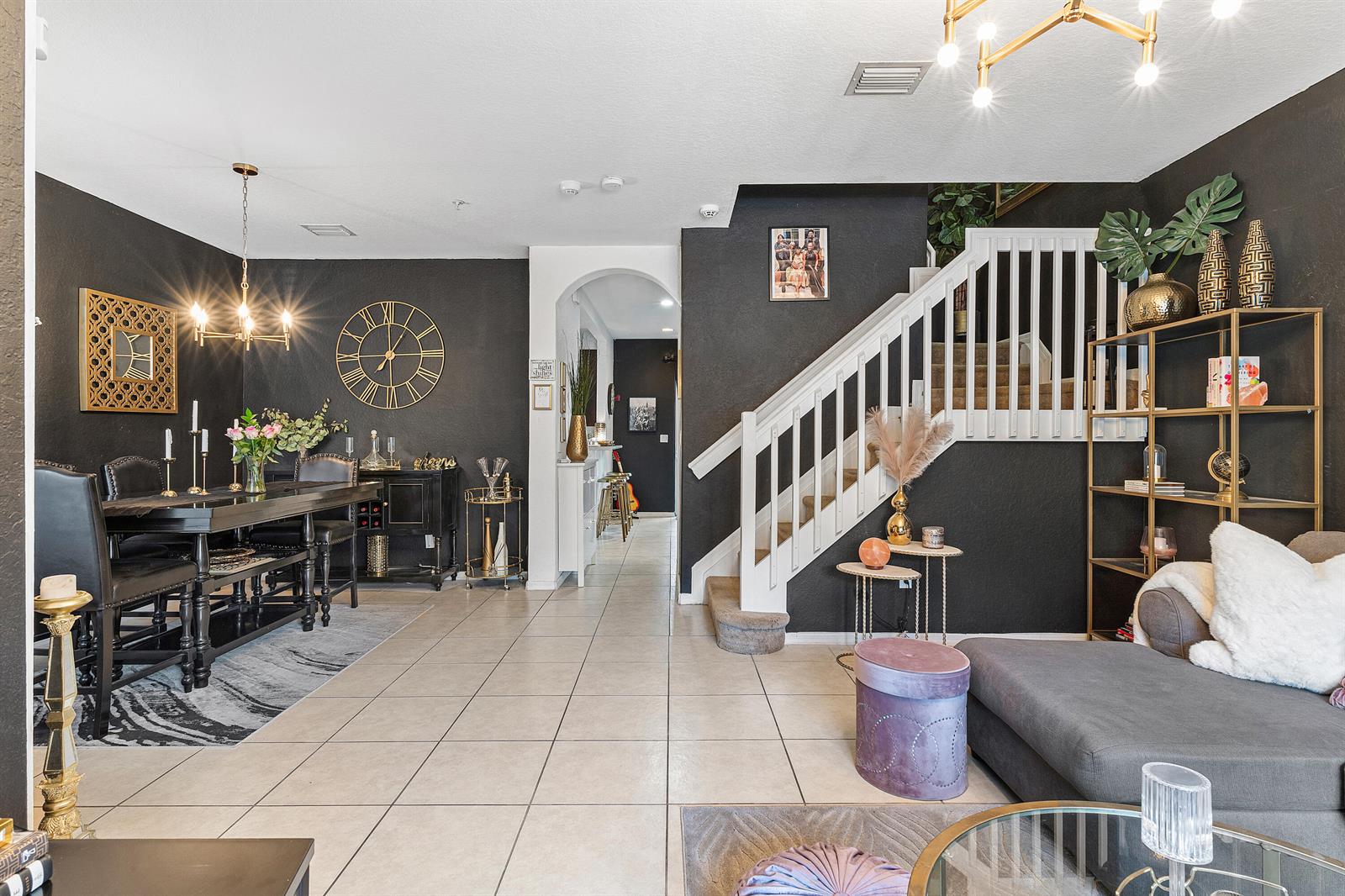 A dining area and living room feature black walls, tile flooring, and a white staircase — 2851 W Prospect # 506, Tamarac FL 33309, TAMARAC, FL