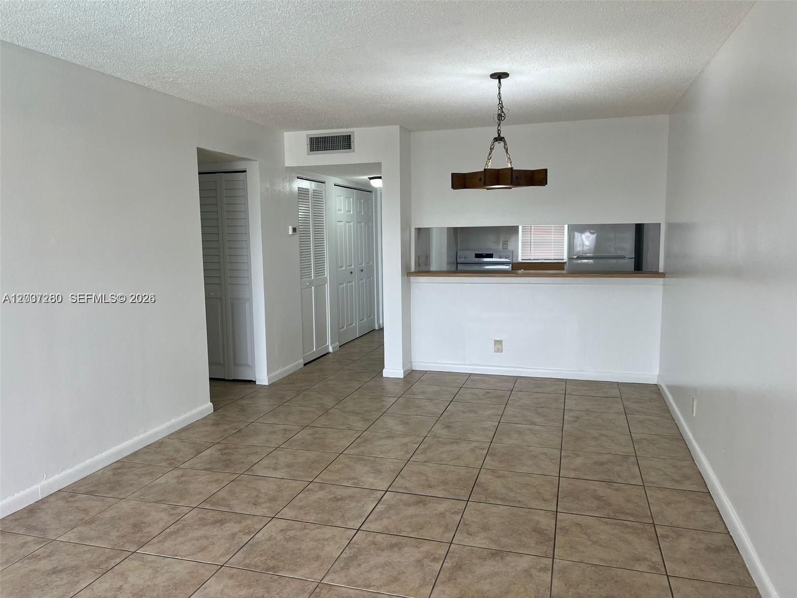 A tiled dining area features a pass-through window to the kitchen and a hanging light fixture — 8610 N Sherman Cir # 504, Miramar FL 33025, MIRAMAR, FL