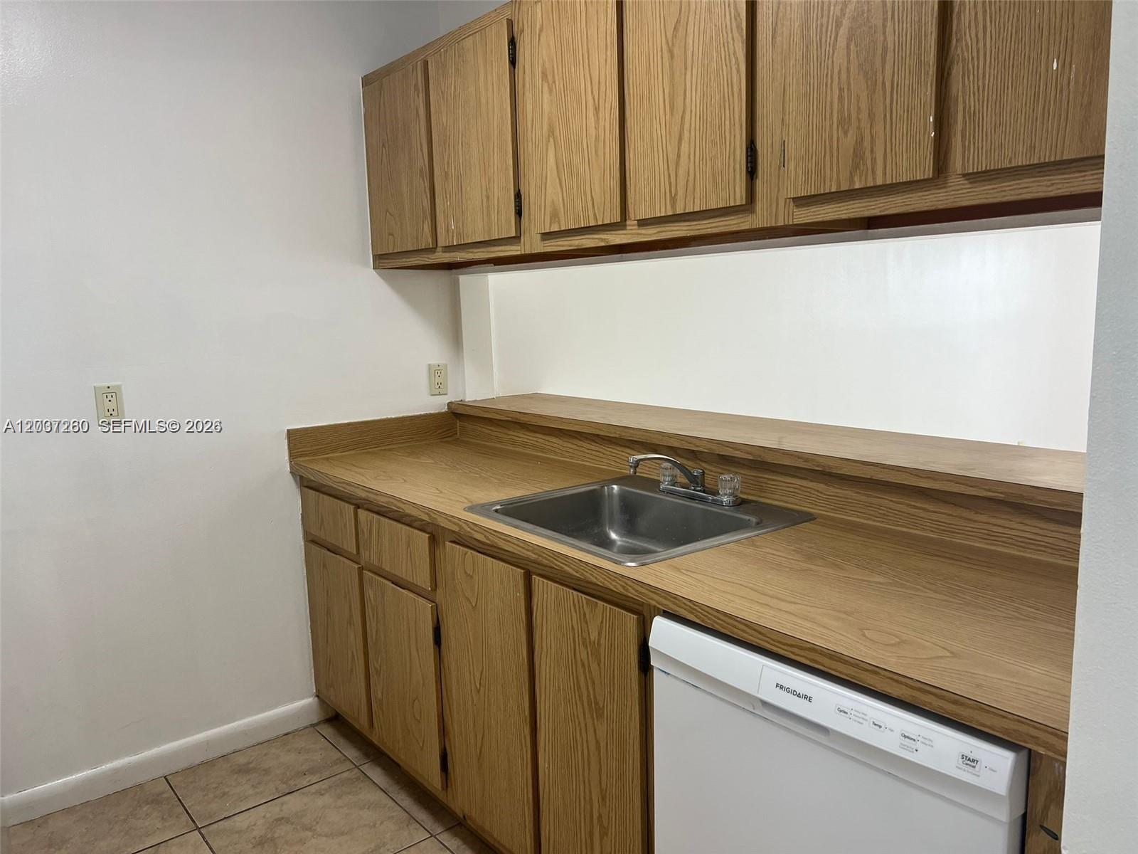 A kitchen features wood cabinets, a stainless steel sink, and a white dishwasher — 8610 N Sherman Cir # 504, Miramar FL 33025, MIRAMAR, FL