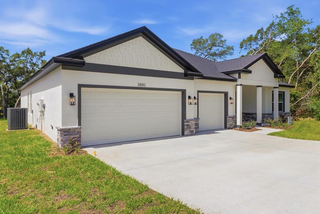 A single-story house with a three-car garage, stone accents, and a concrete driveway — 3880 SW 131ST PLACE RD, OCALA, FL
