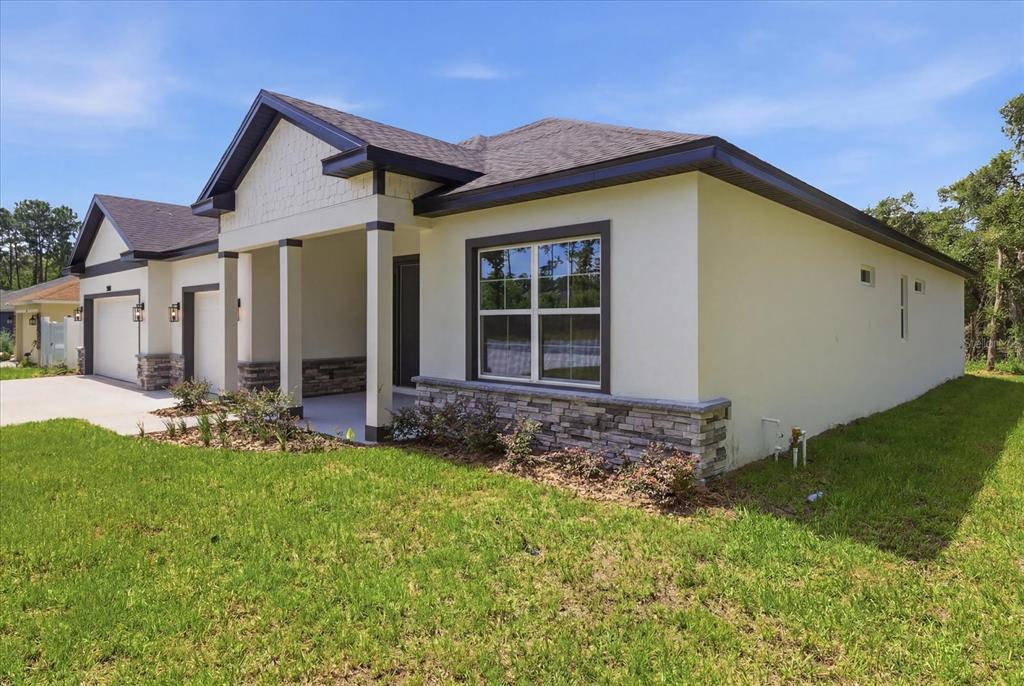 A single-story house with a stucco exterior, stone accents, and a two-car garage — 3880 SW 131ST PLACE RD, OCALA, FL