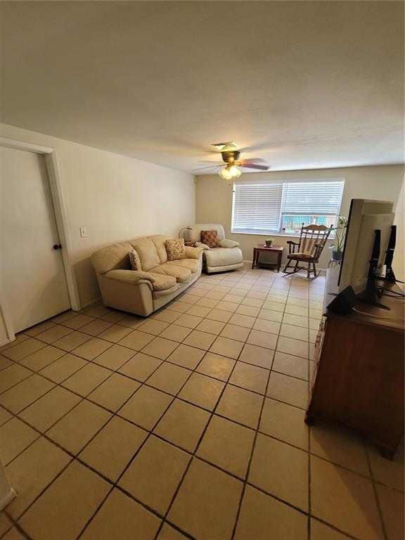 A living room features beige tile flooring, a light-colored sofa, a recliner, and a ceiling fan — 9826 LEHIGH DRIVE, PORT RICHEY, FL