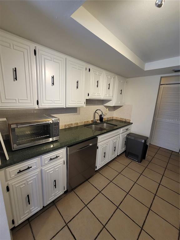 A kitchen features white cabinets, dark green countertops, stainless steel appliances, and tiled flooring — 9826 LEHIGH DRIVE, PORT RICHEY, FL