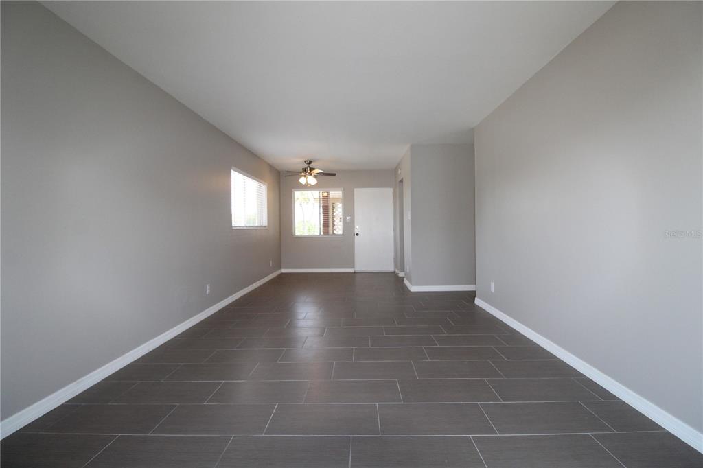 An empty room with gray walls, dark tile flooring, a ceiling fan, and a white door — 3001 BEE RIDGE ROAD UNIT 224, SARASOTA, FL