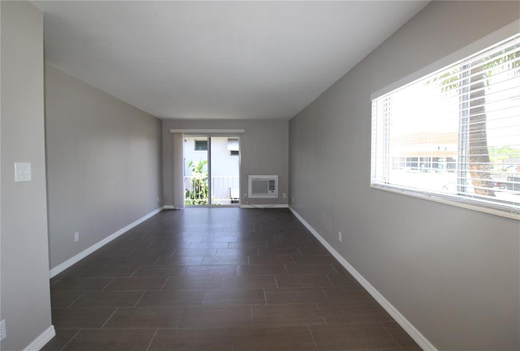 An empty room with gray walls, dark tile flooring, a window, and a sliding glass door — 3001 BEE RIDGE ROAD UNIT 224, SARASOTA, FL