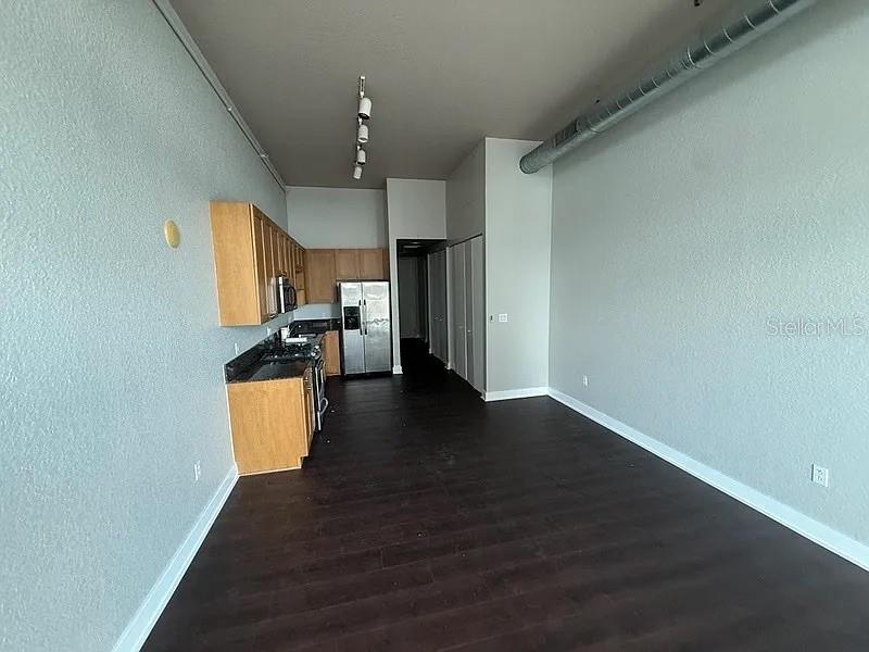 A kitchen with light wood cabinets and dark flooring opens into a spacious living area — 150 E ROBINSON STREET UNIT 627, ORLANDO, FL