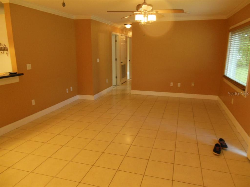 An empty room with tan walls, light-colored tile flooring, and a ceiling fan — 13423 121 ST STREET, SEMINOLE, FL