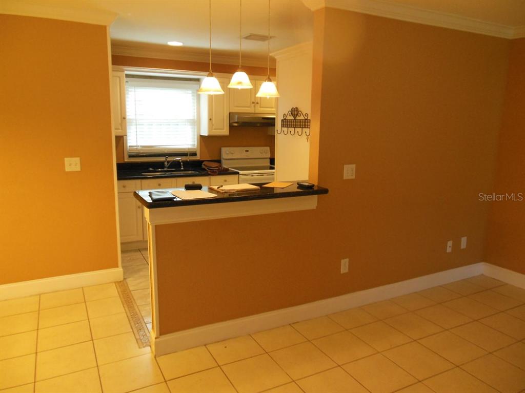 A kitchen with white cabinets, dark countertops, and a breakfast bar overlooks a tiled room — 13423 121 ST STREET, SEMINOLE, FL