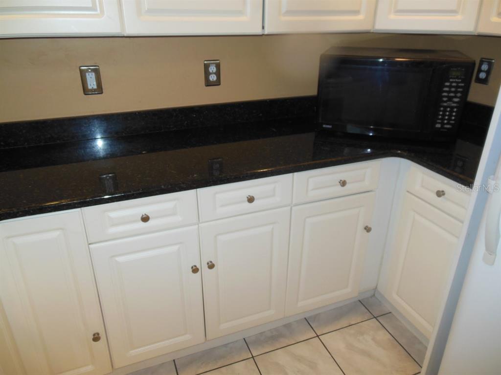 A kitchen features white cabinets, a black countertop, and a microwave on the counter — 13423 121 ST STREET, SEMINOLE, FL