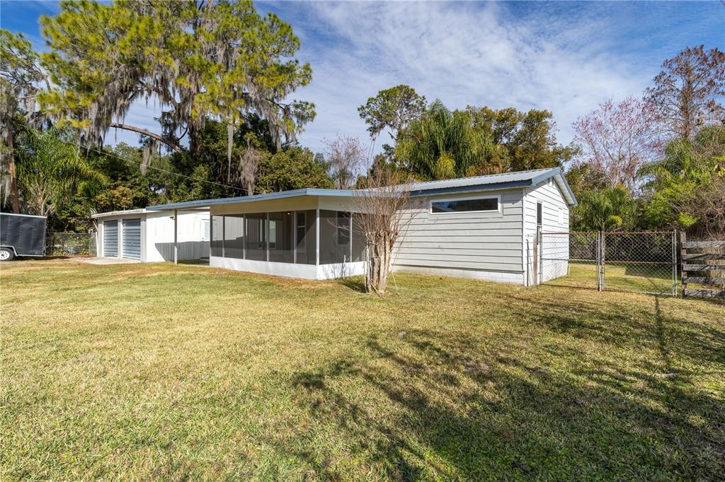 A single-story house with light gray siding, a screened-in porch, and an attached garage — 11807 OCKLAWAHA DRIVE, LEESBURG, FL