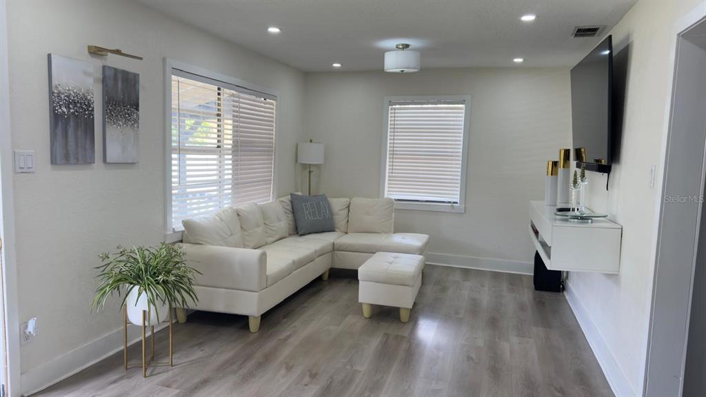 A living room features a white sectional sofa, a matching ottoman, and light wood flooring — 2109 E NAVAJO AVENUE, TAMPA, FL