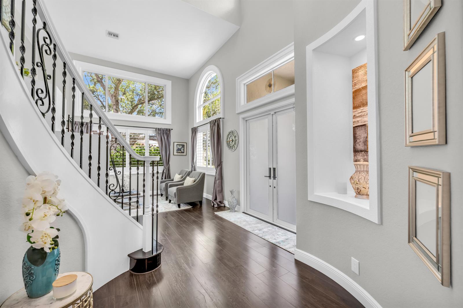 A bright entryway features a curved staircase, hardwood floors, double front doors, and wall niches — 4661 Manderly Drive, Wellington FL 33449, WELLINGTON, FL