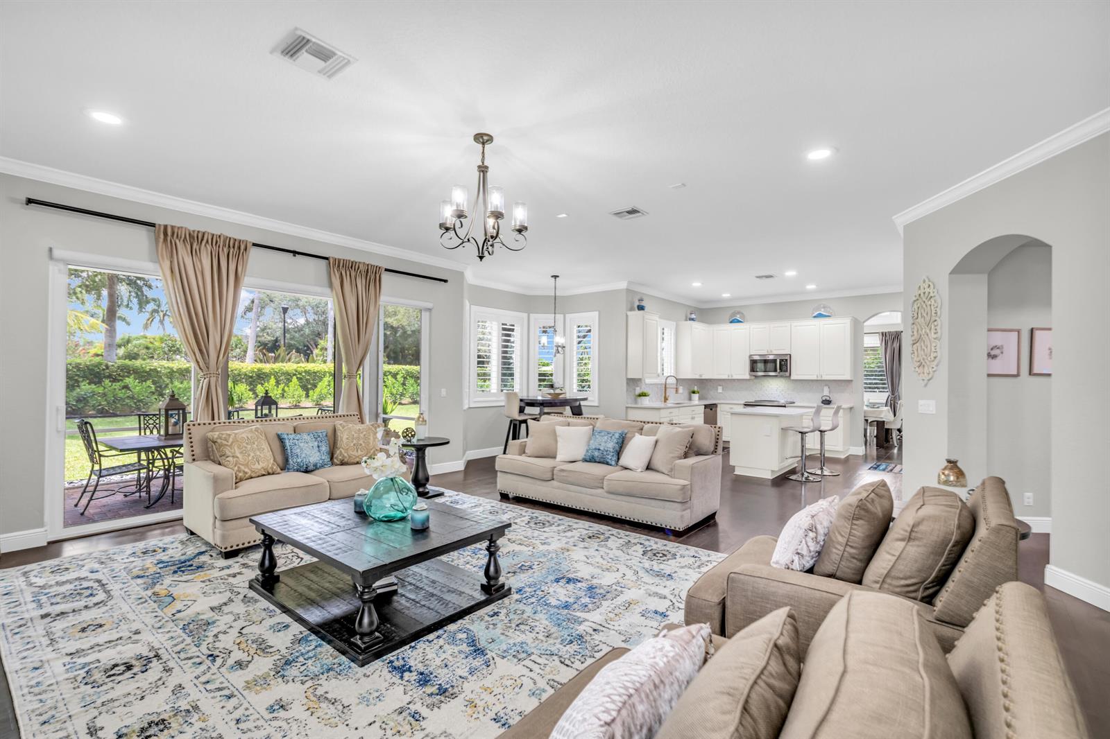 An open-concept living room and kitchen feature neutral furniture, a large patterned rug, and tile floors — 4661 Manderly Drive, Wellington FL 33449, WELLINGTON, FL