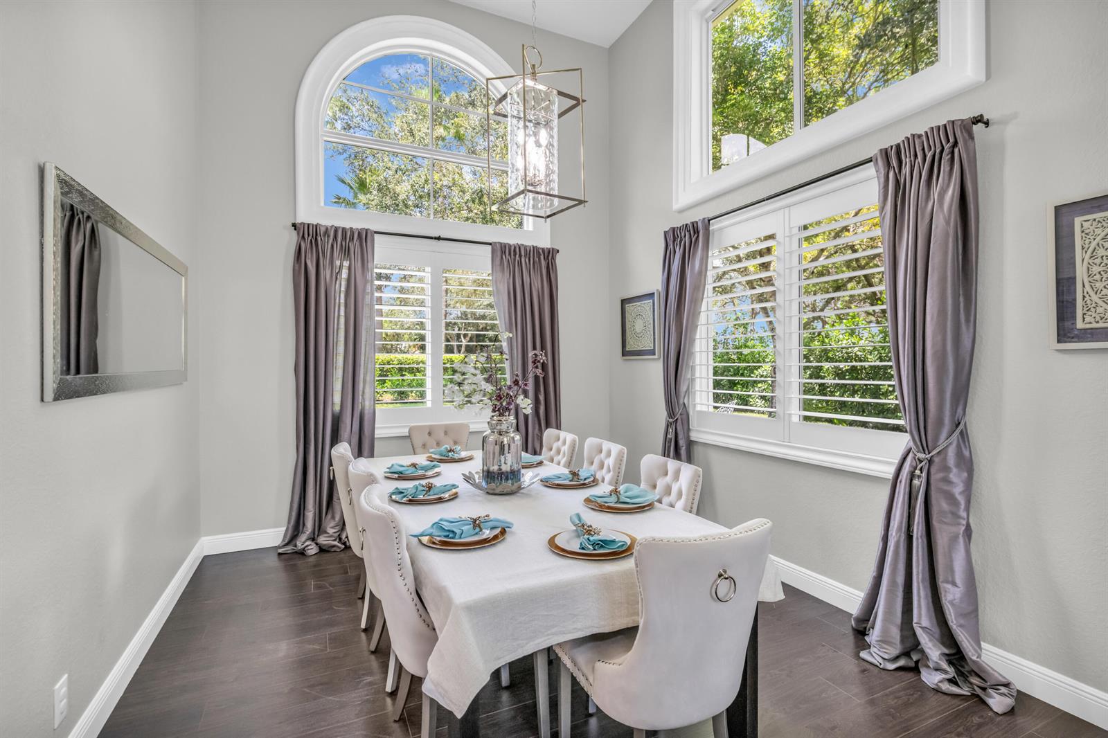 A formal dining room features a long table, upholstered chairs, tall windows, and dark flooring — 4661 Manderly Drive, Wellington FL 33449, WELLINGTON, FL