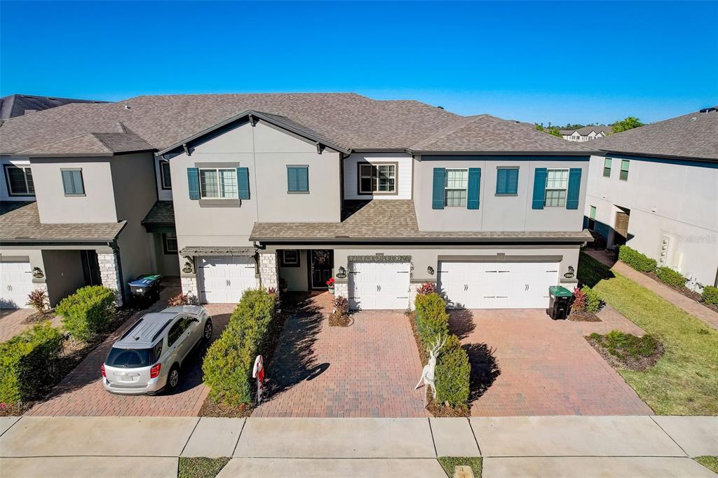 A multi-unit residential building with gray siding, brick driveways, and attached garages under a clear sky — 12043 WHITE WAVE POINT, ORLANDO, FL