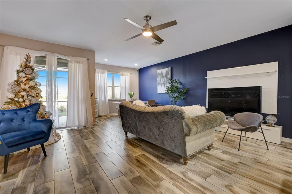 A living room features a dark blue accent wall, wood-look tile flooring, and a Christmas tree — 12043 WHITE WAVE POINT, ORLANDO, FL