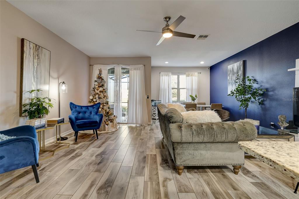 A living room features wood-look tile floors, a blue accent wall, and a Christmas tree — 12043 WHITE WAVE POINT, ORLANDO, FL