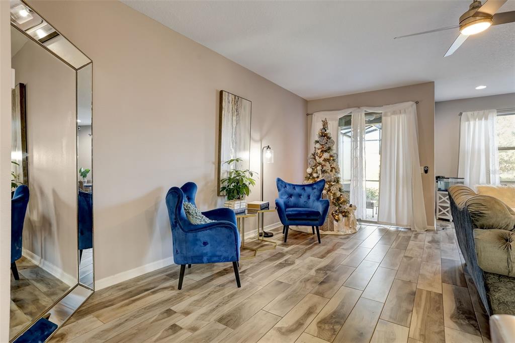 A living area features wood-look tile flooring, two blue velvet armchairs, and a Christmas tree — 12043 WHITE WAVE POINT, ORLANDO, FL