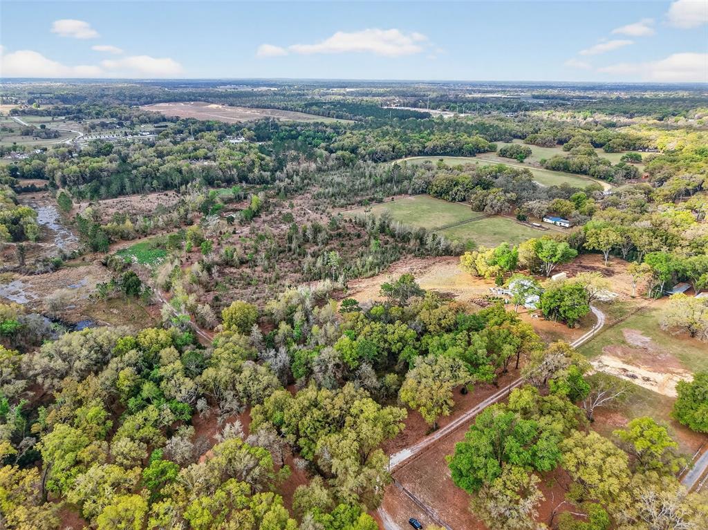 An aerial view shows a large rural property with wooded areas, open fields, and buildings — ISLAND POND LANE, EUSTIS, FL
