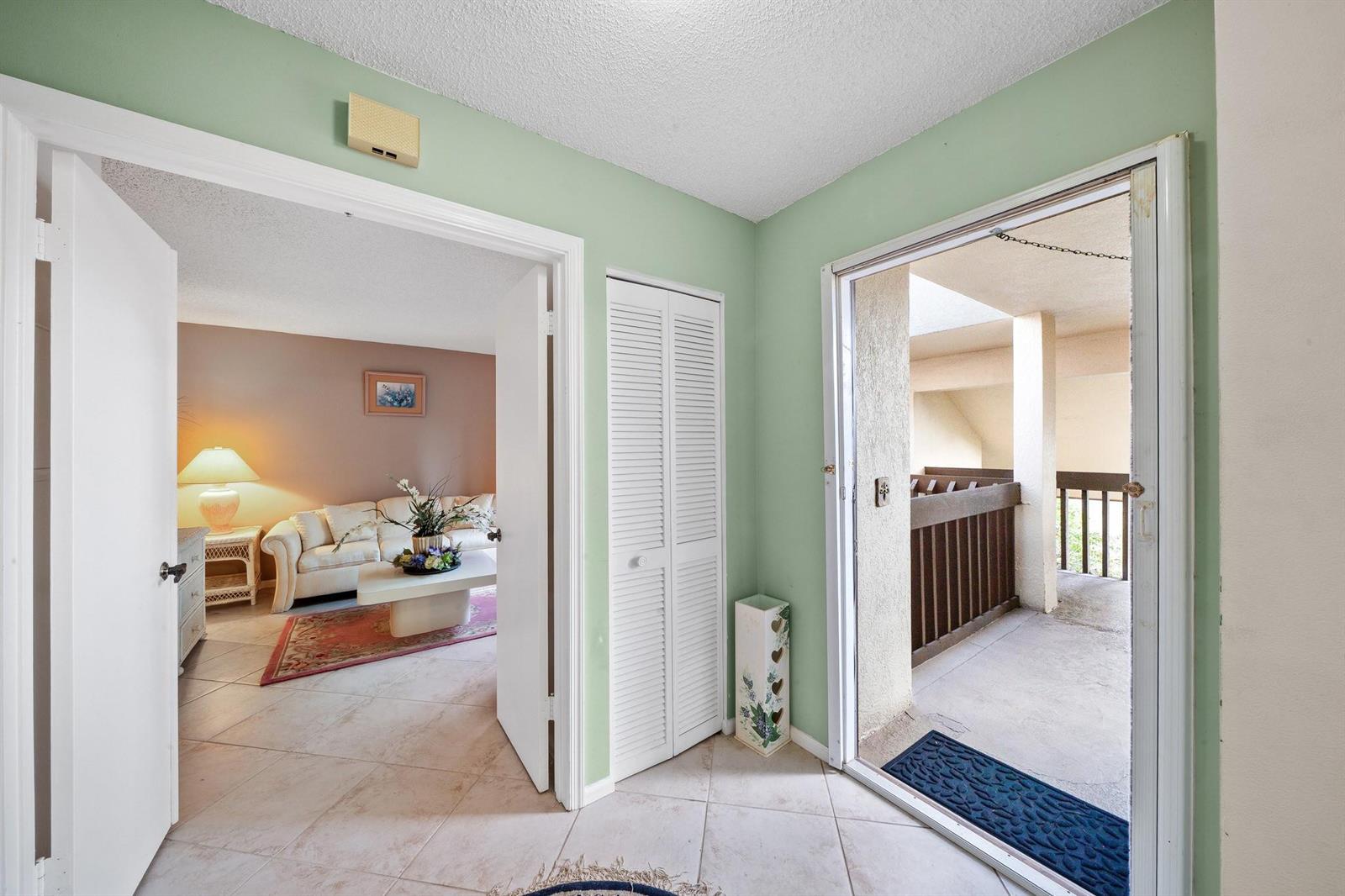 An entryway with light green walls leads to a living room and an outdoor balcony — 5306 Cedar Lake Drive # 203, Boynton Beach FL 33437, BOYNTON BEACH, FL