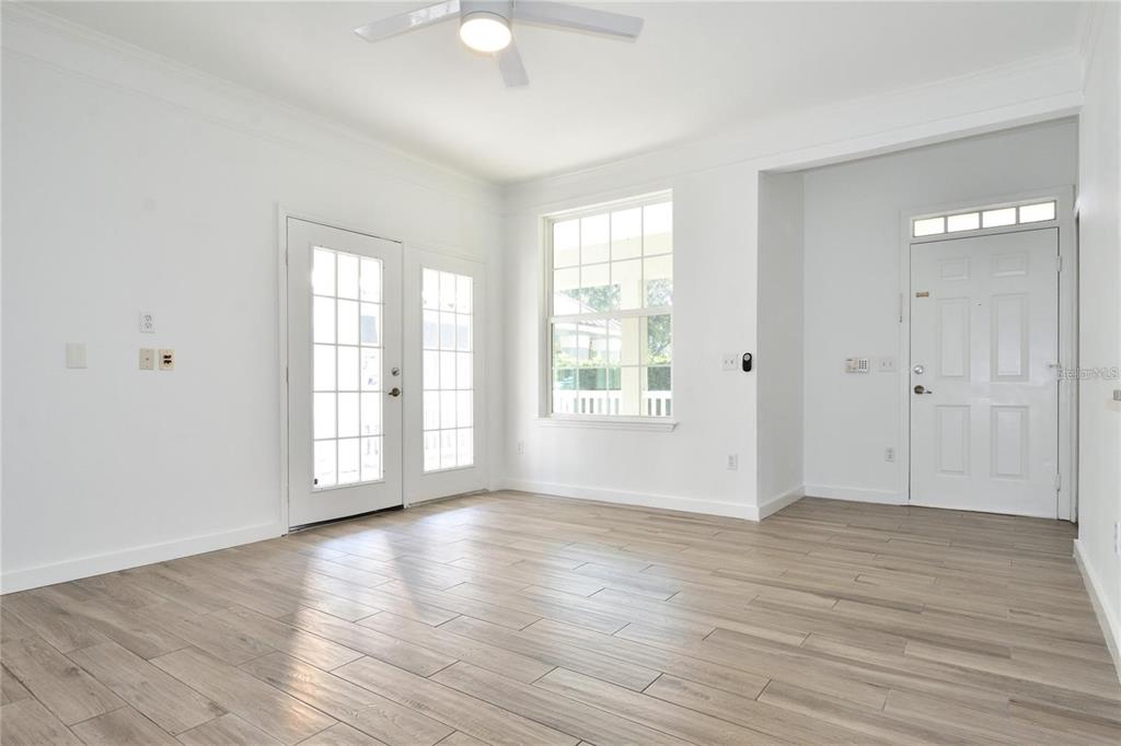 A bright room features white walls, light wood-look tile flooring, a ceiling fan, and doors — 3396 PARKCHESTER SQUARE BOULEVARD UNIT 104, ORLANDO, FL