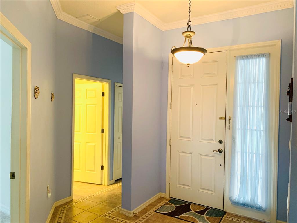 An entryway with light blue walls, tile flooring, a white front door, and a pendant light — 809 SUMMIT GREENS BOULEVARD, CLERMONT, FL
