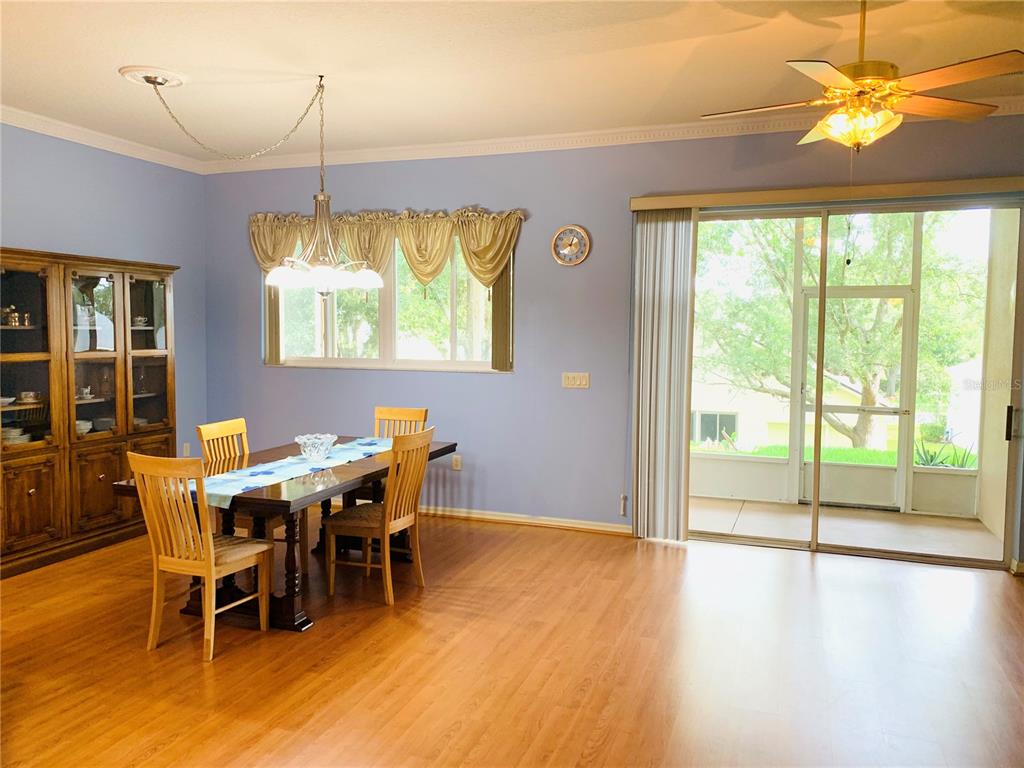 A dining room with light blue walls, wood flooring, a wooden table, and sliding glass doors — 809 SUMMIT GREENS BOULEVARD, CLERMONT, FL
