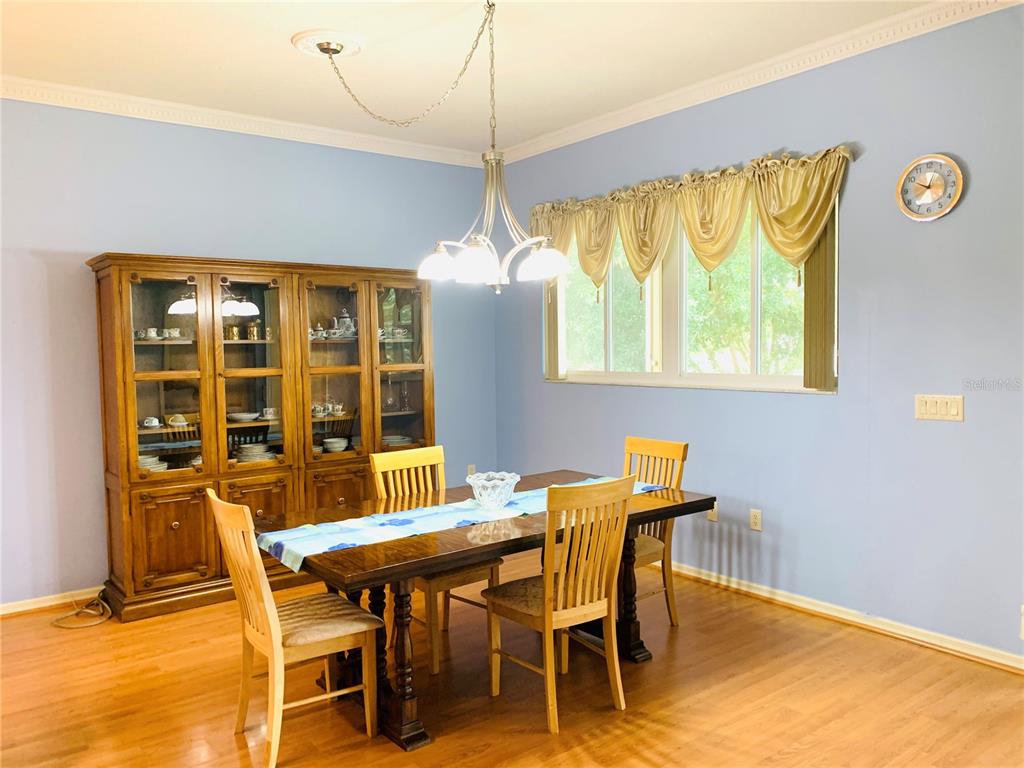 A dining room features a wooden table, chairs, a hutch, and a chandelier on blue walls — 809 SUMMIT GREENS BOULEVARD, CLERMONT, FL