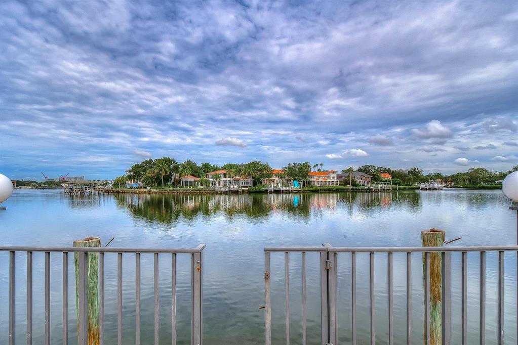 A view across a calm body of water toward several waterfront houses under a cloudy sky — 4929 W BAY WAY DRIVE, TAMPA, FL