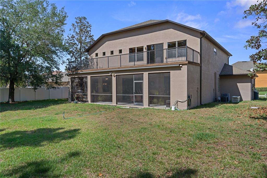 The rear exterior of a two-story house features a screened-in patio and an upper balcony — 14807 PRINCEWOOD LANE, LAND O LAKES, FL