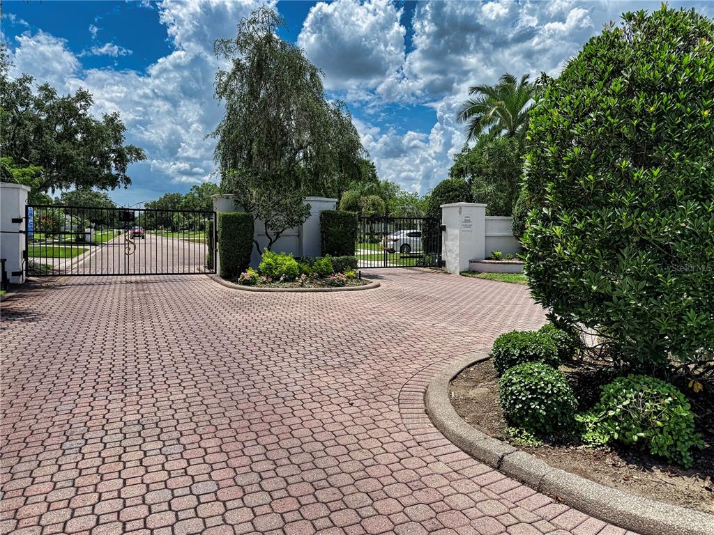 A gated entrance with a brick paver driveway and landscaped garden beds — 905 SQUARE LAKE DRIVE, BARTOW, FL