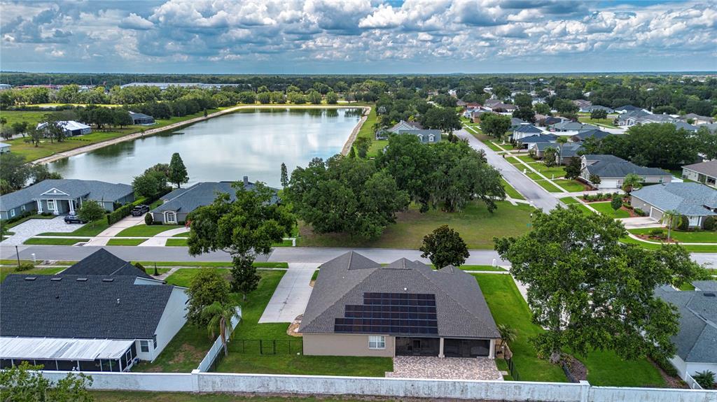 An aerial view shows a suburban house with solar panels and a backyard pool cage — 905 SQUARE LAKE DRIVE, BARTOW, FL
