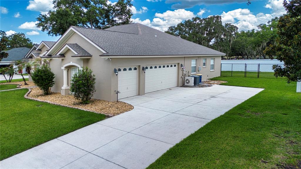 An exterior view of a beige house with a three-car garage and a concrete driveway — 905 SQUARE LAKE DRIVE, BARTOW, FL