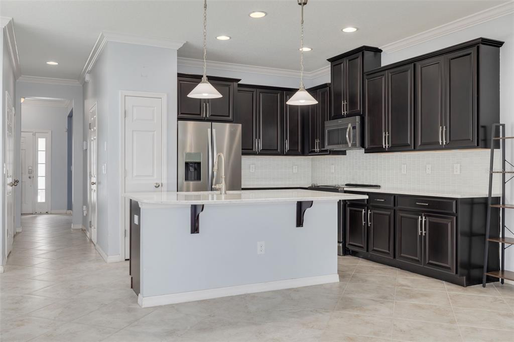 A kitchen features dark wood cabinets, stainless steel appliances, a white island, and tile flooring — 4087 69TH TERRACE N, PINELLAS PARK, FL