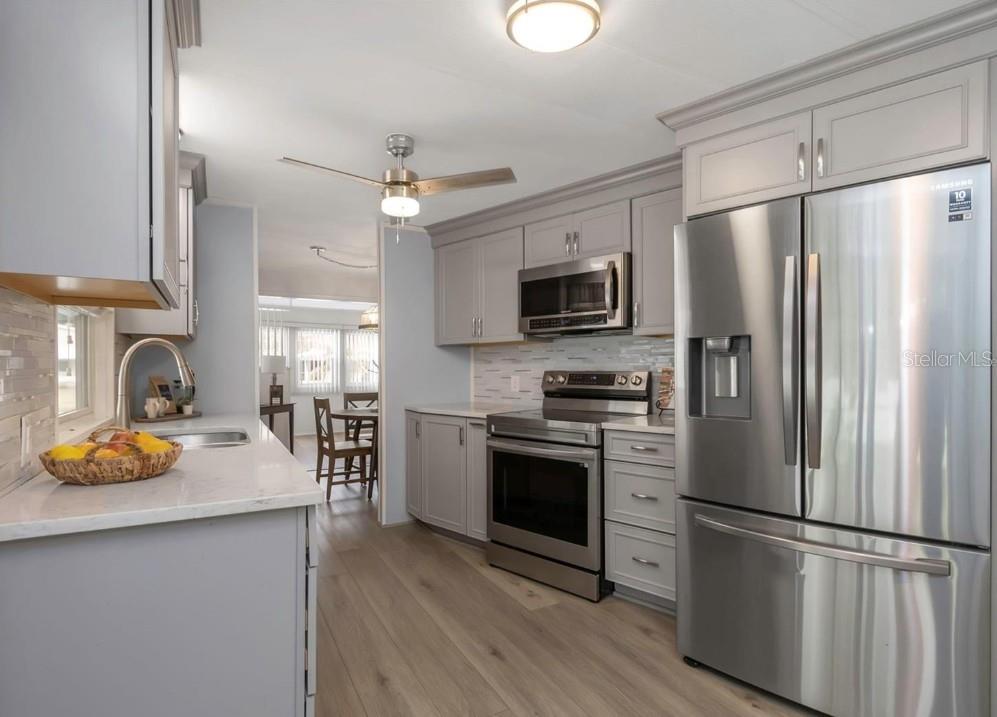 A kitchen with gray cabinets, stainless steel appliances, and light wood-look flooring — 198 PHILADELPHIA BOULEVARD UNIT 11, PALM HARBOR, FL