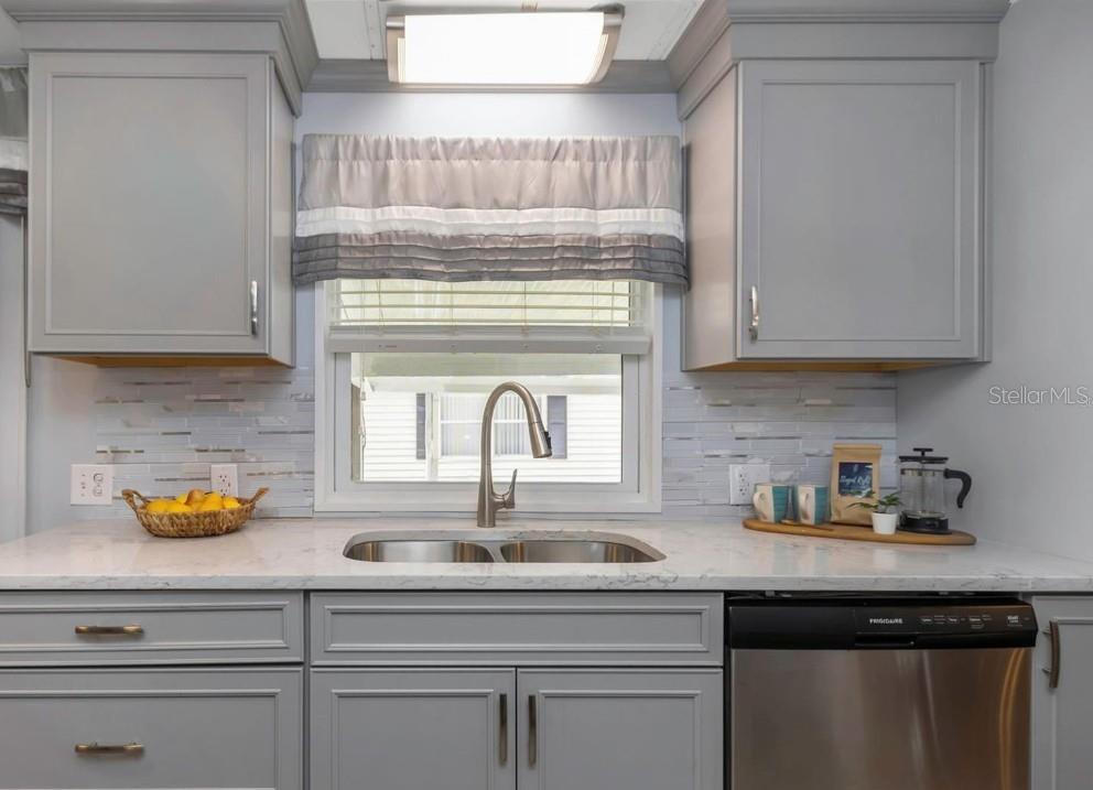 A kitchen sink area features gray cabinets, a white countertop, and a tiled backsplash — 198 PHILADELPHIA BOULEVARD UNIT 11, PALM HARBOR, FL