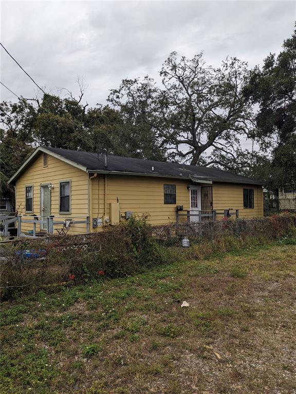A yellow, single-story house with a dark roof, wooden decks, and a chain-link fence — 2412 E DR MARTIN LUTHER KING JR BOULEVARD, TAMPA, FL