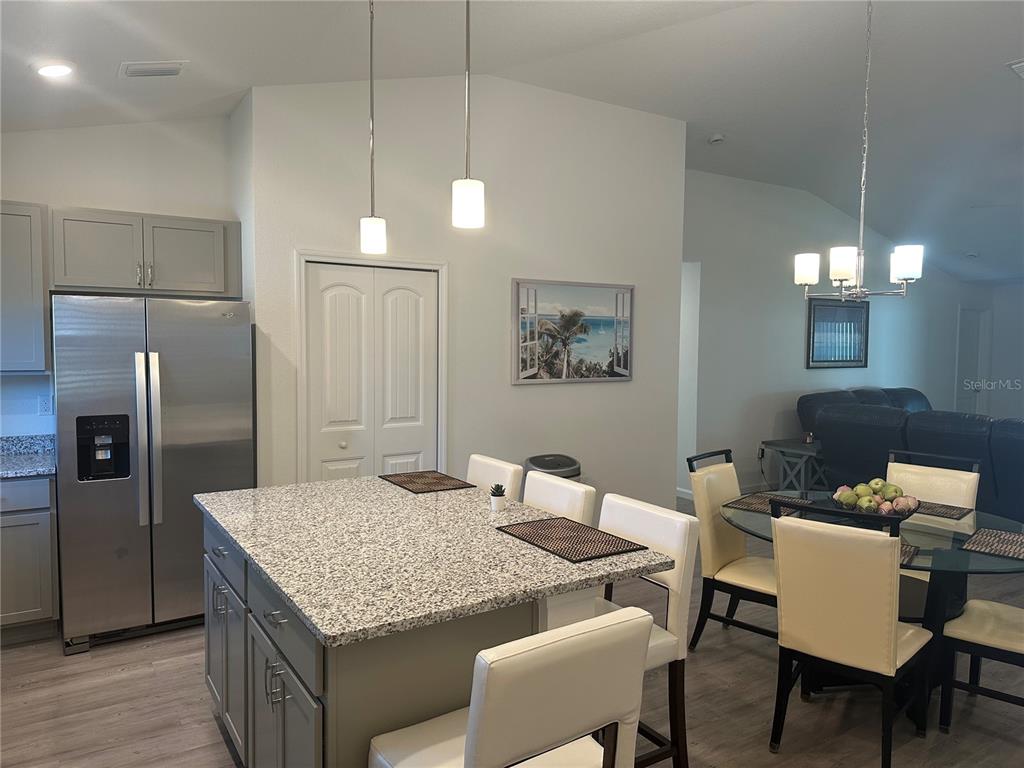 A kitchen features a granite-topped island, stainless steel refrigerator, and an adjacent dining area — 30 PIEDMONT DRIVE, PALM COAST, FL