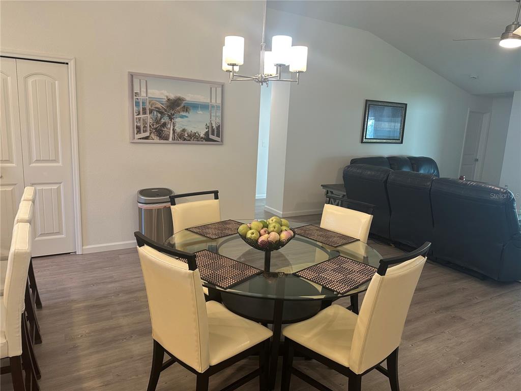 A dining area features a glass-topped table with four chairs under a modern chandelier — 30 PIEDMONT DRIVE, PALM COAST, FL