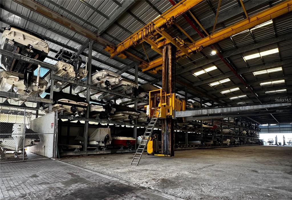 A large indoor boat storage facility features multi-level metal racks and a yellow overhead crane — 408 GULF OF MEXICO DRIVE UNIT 2112, LONGBOAT KEY, FL