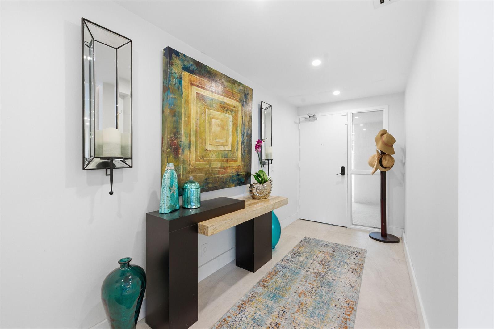 A modern entryway features a console table, abstract wall art, a rug, and a coat rack — 3972 N Ocean Drive # 5, Singer Island FL 33404, SINGER ISLAND, FL