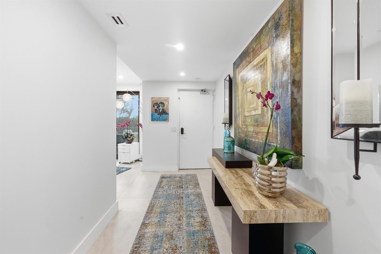 A modern entryway features a stone console table, a large abstract painting, and a runner rug — 3972 N Ocean Drive # 5, Singer Island FL 33404, SINGER ISLAND, FL