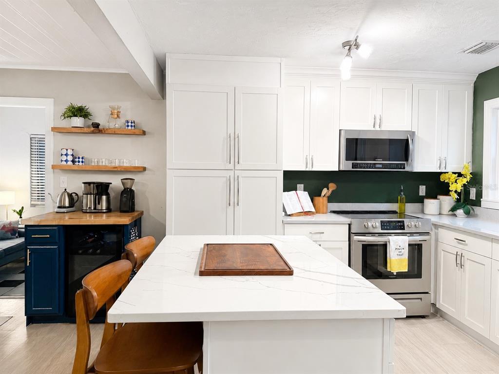 A kitchen features white cabinetry, a marble-topped island, and a dark blue coffee bar area — 926 29TH STREET N, ST PETERSBURG, FL