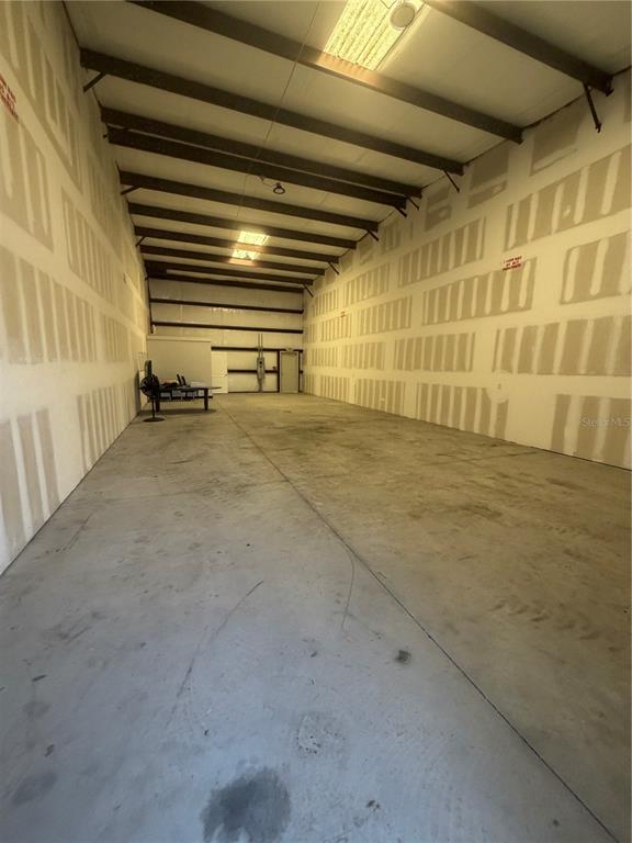 An empty warehouse interior features concrete floors and unfinished drywall walls with exposed ceiling beams — 5475 DOVE DRIVE UNIT 15, NEW PORT RICHEY, FL