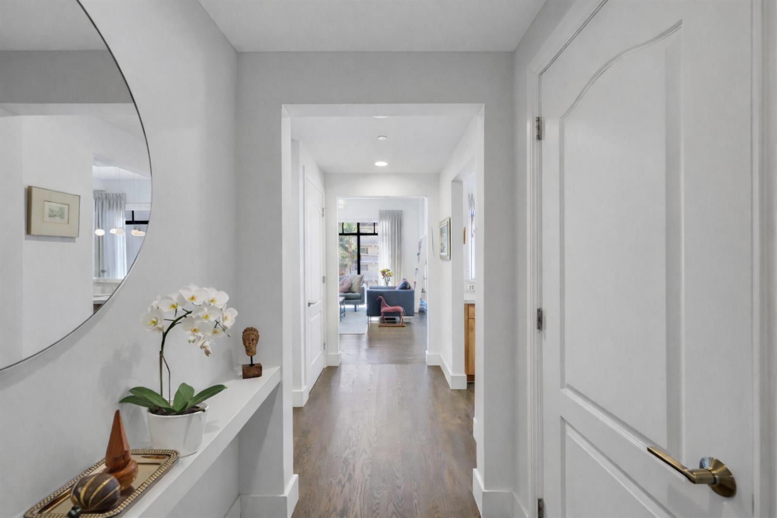 A bright hallway with white walls, hardwood floors, a floating shelf, and a round mirror — 200 E Palmetto Park Road # 7, Boca Raton FL 33432, BOCA RATON, FL