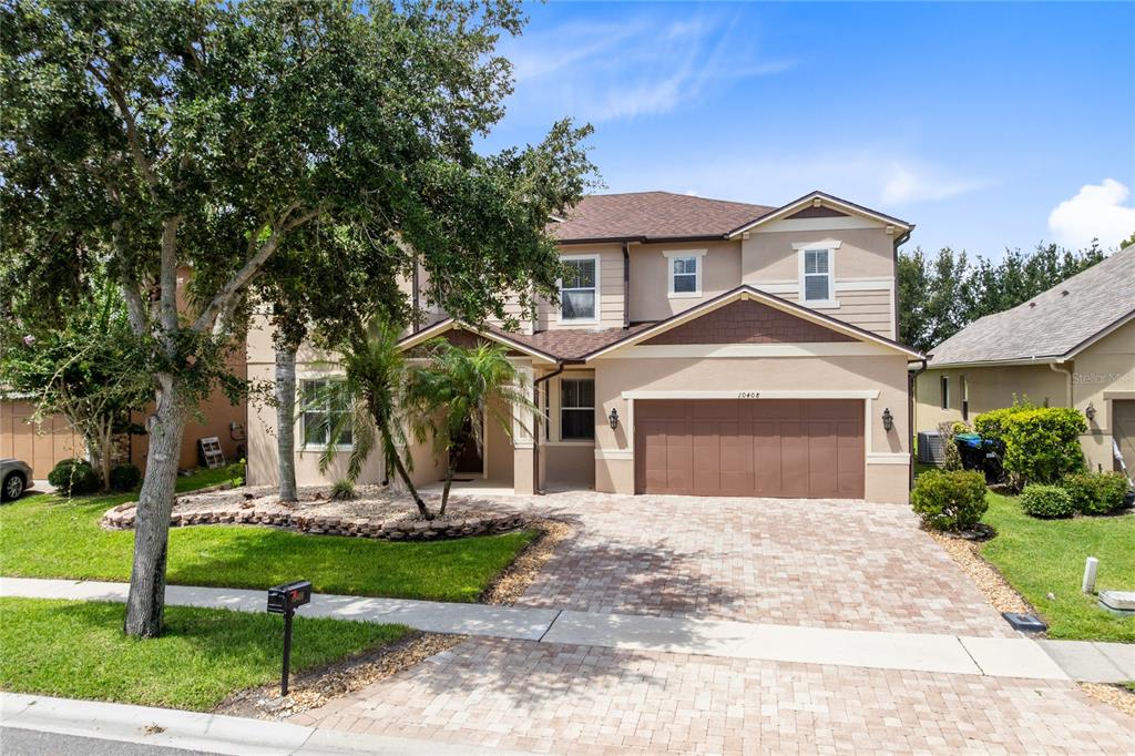 A two-story suburban house features a paved driveway, a two-car garage, and landscaping — 10408 CHORLTON CIRCLE, ORLANDO, FL