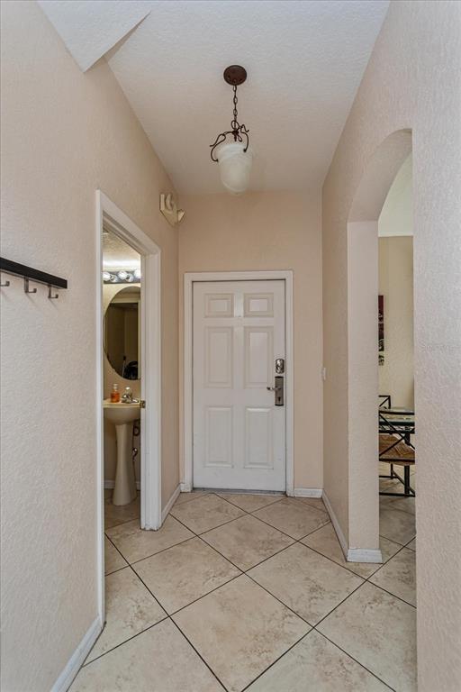 An entryway features a white door, tiled floors, a pendant light, and an adjacent bathroom — 232 LA MIRAGE STREET, DAVENPORT, FL