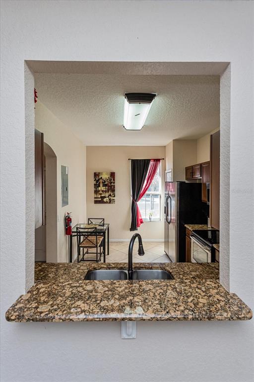 A kitchen pass-through window overlooks a dining area with a table, chairs, and window curtains — 232 LA MIRAGE STREET, DAVENPORT, FL