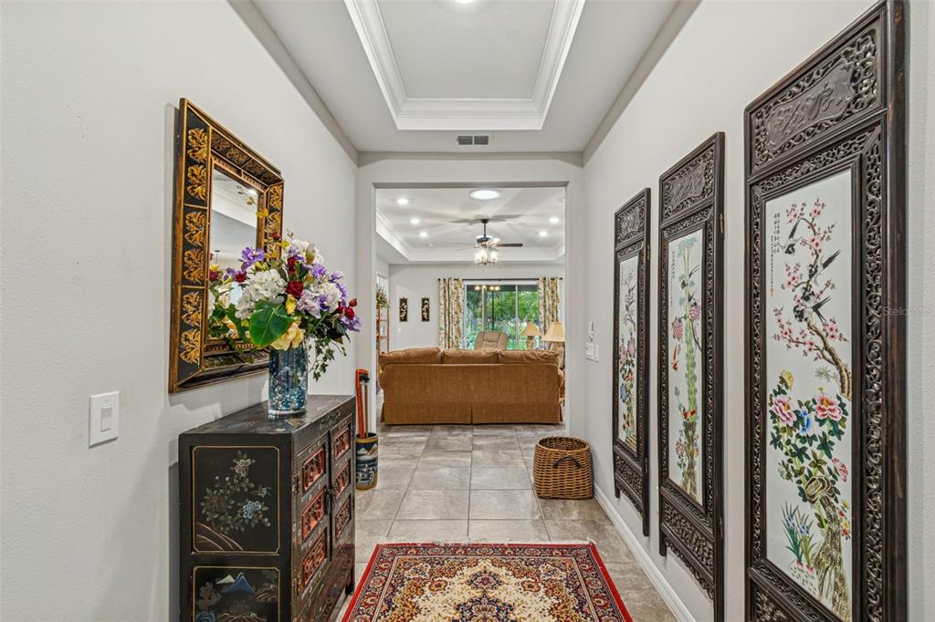 A hallway with a tray ceiling leads to a living room with tile flooring — 795 AVIARA LANE, KISSIMMEE, FL